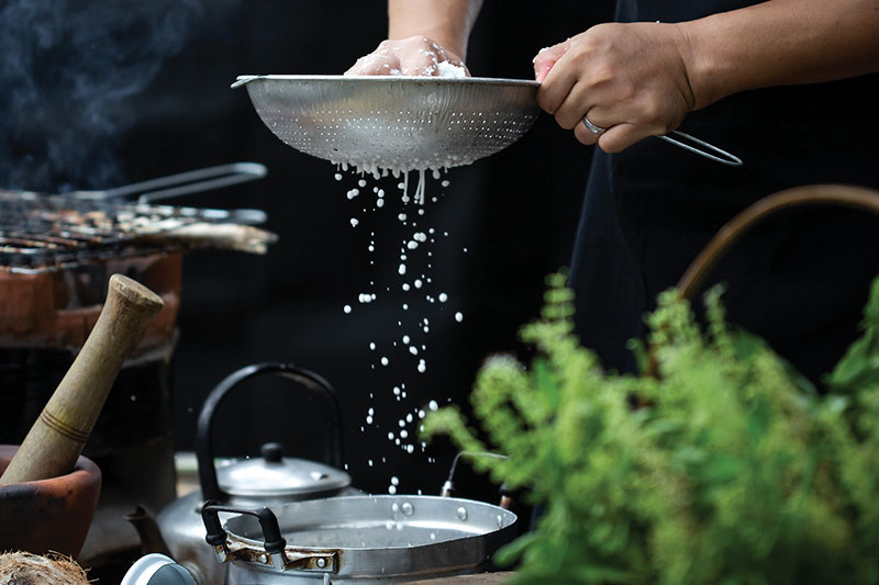 Chef Santi squeezes grated coconut through a sieve to make coconut milk<br />
