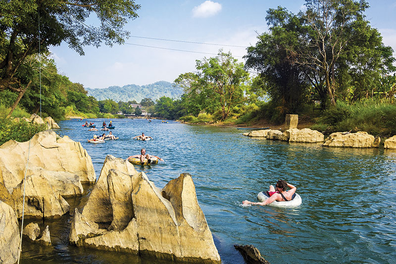 Travellers float down a calm river in Vang Vieng
