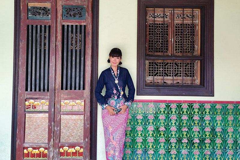 A young woman<br />
in Thai Baba Kebaya stands before a beautifully preserved Sino-European shophouse in Phuket Old Town