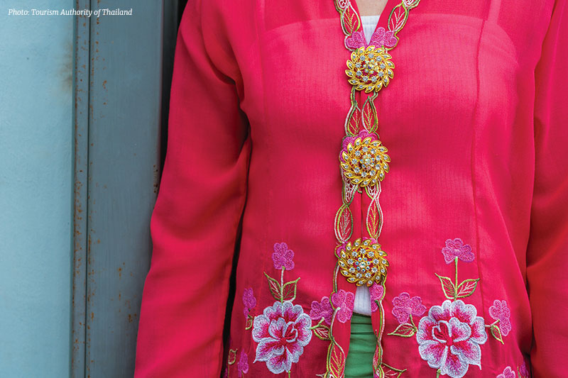 Three ornate gold brooches fasten the kebaya, replacing buttons in a tradition passed down through generations